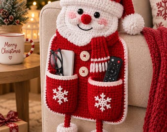 Peut inclure: Un organisateur en crochet rouge et blanc représentant le Père Noël, avec un bonnet, une barbe, deux poches ornées de flocons de neige blancs, deux boutons beiges et des jambes pendantes terminées par des bottes rouges.