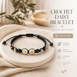Puede incluir: Una pulsera de ganchillo negra con detalles de flores de margarita y cuentas plateadas. La pulsera está sobre una superficie de cerámica blanca. La imagen incluye el texto "CROCHET DAISY BRACELET" y "CROCHET PDF PATTERN".