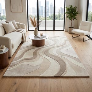 May include: A rectangular area rug featuring a flowing, wavy pattern in shades of cream, beige, and light brown. The rug has a textured, multi-level pile that creates depth through its curved, organic lines, covering a light-toned wooden floor.