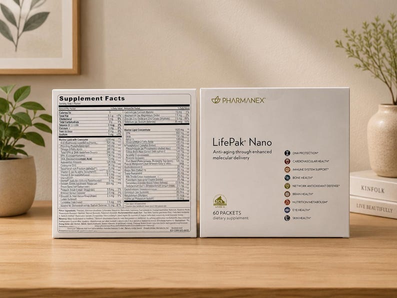 Two Pharmanex LifePak Nano supplement boxes displayed on a wooden table in a modern home-style setup with decorative plants, books, soft beige wall background, and natural indoor lighting.