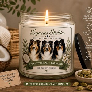 Peut inclure: Une bougie parfumée allumée dans un pot en verre avec un couvercle noir. L'étiquette indique "Legacies Shelties" avec des portraits de chiens et "Coconut Cream + Cardamom". Une étiquette dit "Cadeau parfait pour les amoureux de Sheltie !" La bougie est de 255g.