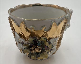 Taza de porcelana alemana blanca con relieve dorado y diseño floral pintado. Objeto de colección.