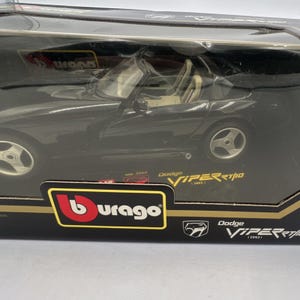 Puede incluir: Un coche modelo Dodge Viper RT/10 negro en su embalaje original. El coche modelo es un descapotable con interior beige. El embalaje incluye el logotipo de Burago y el texto "Dodge Viper RT/10 (1993)".