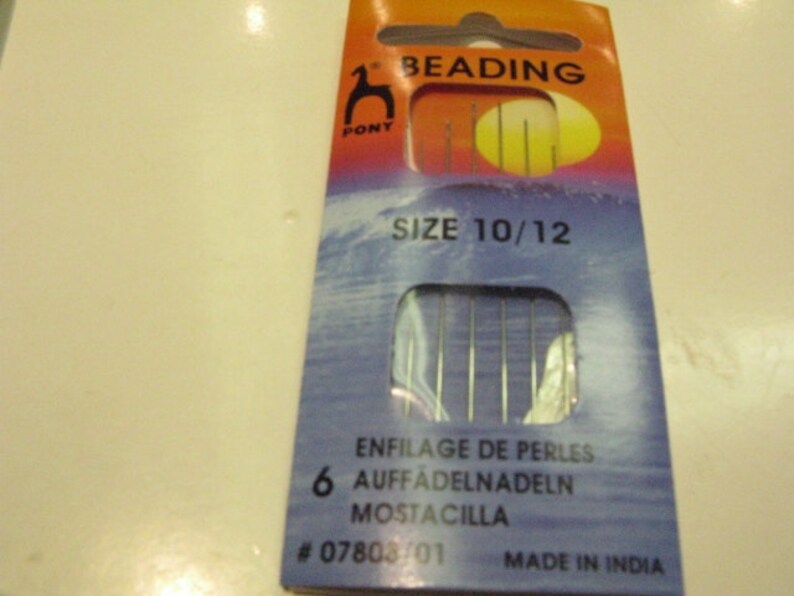 May include: A pack of 6 Pony beading needles, size 10/12, in a blue and orange packet with the text "BEADING" and "SIZE 10/12". The packet also includes the text "ENFILAGE DE PERLES", "AUFFADELNADELN", "MOSTACILLA", "#07803/01", and "MADE IN INDIA".