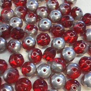May include: A collection of red and silver faceted glass beads. The beads are round and have a hole in the center. They are perfect for jewelry making or other craft projects.