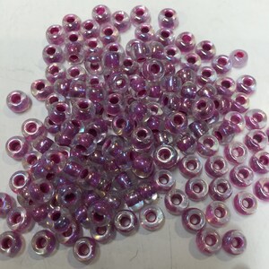 May include: A large quantity of iridescent pink seed beads. The beads are round and have a small hole in the center. They are perfect for jewelry making or other craft projects.