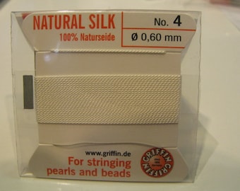 May include: A white spool of natural silk thread for stringing pearls and beads. The spool is labelled "NATURAL SILK 100% Naturseide No. 4 Ø 0,60 mm" and "www.griffin.de For stringing pearls and beads".