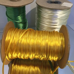 May include: Three spools of thread, one green, one white, and one yellow. The spools are made of cardboard and have a wooden center.