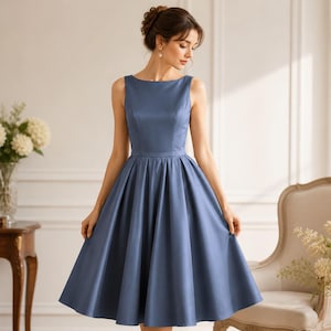 Puede incluir: Un vestido sin mangas, hasta la rodilla, en un tono azul polvoriento. El vestido presenta un corpiño ajustado, una cintura definida y una falda acampanada. El vestido tiene un diseño clásico y elegante, adecuado para eventos formales u ocasiones especiales.