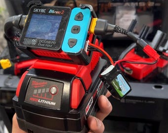 May include: A SkyRC B6neo 2 battery charger with a blue control panel attached to a red and black Milwaukee M18 RedLithium XC4.0 battery pack. The charger features a digital display screen, navigation buttons, and a connected small black battery.