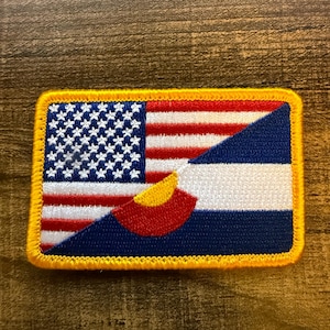 May include: A rectangular embroidered patch featuring a split design. The left side displays the United States flag with white stars on a blue field and red and white stripes. The right side shows the Colorado state flag with blue, white, and blue horizontal stripes and a red C with a yellow center.