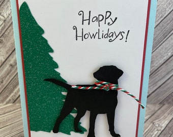 May include: A handmade greeting card with a black dog silhouette and a green glitter Christmas tree. The card reads "Happy Howlidays!" in black script, with a red, green, and white twine collar.
