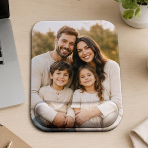 Peut inclure: Un tapis de souris rectangulaire avec une photographie imprimée d'une famille de quatre personnes, deux adultes et deux enfants, tous souriants. Le tapis de souris possède un repose-poignet intégré en bas et des coins arrondis.