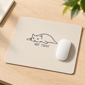 Può includere: Un tappetino per mouse beige con un disegno a contorno nero di un gatto e la scritta "NOT TODAY". Un mouse per computer bianco è accanto al tappetino. Il tappetino è su una superficie di legno chiaro.