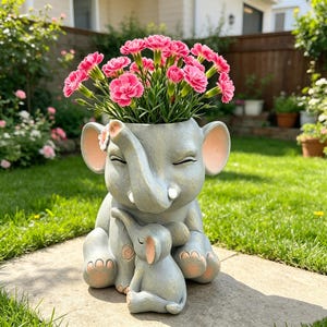 May include: A grey elephant-shaped plant pot with a baby elephant, filled with pink carnations. The pot has a smiling face and large ears with pink accents. The scene is set outdoors on a sunny day.