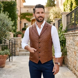 Può includere: Un gilet in pelle marrone con texture di struzzo, caratterizzato da revers a dente, cinque bottoni frontali e due tasche a filetto. Il gilet è indossato sopra una camicia bianca a maniche lunghe, pantaloni blu scuro e un orologio da polso.