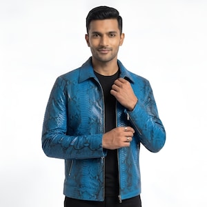 May include: A vibrant blue jacket featuring a detailed black snakeskin pattern throughout. The garment includes a classic collar, a full-length front zipper closure, and long sleeves with zippered cuffs. It is worn over a plain black shirt.