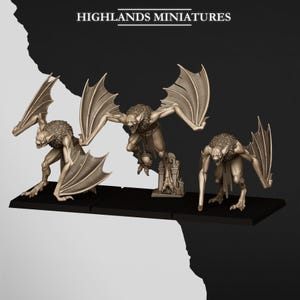 Könnte beinhalten: Drei beige Miniaturfiguren mit der Aufschrift HIGHLANDS MINIATURES, die jeweils ein geflügeltes, fledermausartiges Wesen mit scharfen Zähnen und behaarten Schultern darstellen. Die Figuren sind auf einzelnen schwarzen quadratischen Sockeln montiert.