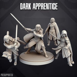 Könnte beinhalten: Vier hellgraue Miniaturfiguren mit der Aufschrift DARK APPRENTICE, die jeweils eine Person mit schulterlangem Haar in Tunika, Rüstung und Umhang darstellen. Die Figuren zeigen verschiedene Kampfposen, einige halten Schwerter, eine Figur trägt eine Kapuze.