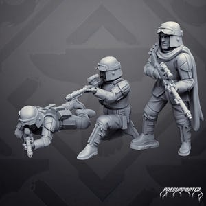 Può includere: Tre statuette di soldati in miniatura di colore grigio con equipaggiamento tattico, inclusi elmetti con occhiali protettivi e fucili. Un soldato è sdraiato, uno è in ginocchio e uno è in piedi. Il testo "PRESUPPORTED" è visibile in basso a destra.