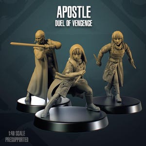 Könnte beinhalten: Drei beigefarbene Miniaturfiguren auf schwarzen runden Sockeln. Der Text lautet APOSTLE DUEL OF VENGENCE und 1:48 SCALE PRESUPPORTED. Die Figuren sind in Kampfposen dargestellt und tragen strukturierte Tuniken, Kapuzen und Rüstungen mit Waffen.