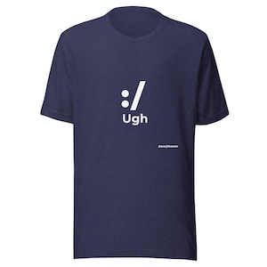 May include: A navy blue short-sleeved t-shirt featuring a white graphic print on the chest. The design includes a colon and a forward slash symbol, the word "Ugh" printed below it, and the small text "EmojiTeecon" in the lower right area.