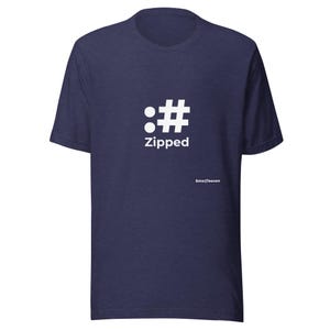 May include: A navy blue short-sleeved t-shirt featuring a white graphic on the chest. The graphic displays a colon and a hashtag symbol above the word Zipped in white text. A small white EmojTeecon logo is printed near the bottom right area.