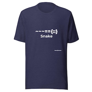 以下が含まれることがあります： 胸元に白いグラフィックプリントが施されたネイビーブルーの半袖Tシャツ。デザインには記号「~~~=={::}」と「Snake」という単語が含まれており、メイングラフィックの下には小さな文字で「EmojTeecon」と記されています。