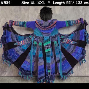 May include: A long, hooded coat in shades of blue, purple, and black, featuring a patchwork design with frayed edges, decorative embroidery, and long fabric strips. The garment is labelled #534, size XL-XXL, with a length of 132 cm.
