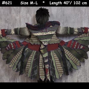 Peut inclure: Un manteau unique de style patchwork avec une capuche, composé d'un mélange de tissus verts, bordeaux et à motifs. La longueur du manteau est de 102 cm. Le design incorpore diverses textures et motifs, créant un look artistique distinctif. Taille M-L.