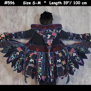 May include: A black hooded cardigan with a colorful patchwork design and ruffled trim. The cardigan is 39 inches long and has a size of S-M. #596