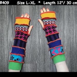 May include: A pair of multi-coloured arm warmers with a length of 30 cm. The design incorporates various patterns and textures, including geometric and star motifs. The colour palette includes yellow, red, blue, and green, creating a vibrant appearance.