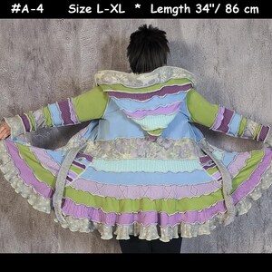 May include: A multi-colored hooded cardigan with a ruffled hem. The cardigan is made of a patchwork of different fabrics in shades of green, purple, blue, and white. The cardigan is 34 inches long and is available in sizes L-XL. #A-4