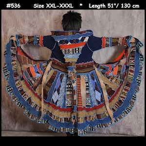 May include: A blue, multi-coloured, patchwork cardigan with a long, flowing skirt. The cardigan has a high collar and is made of different types of knit fabric. The skirt is made of a variety of fabrics, including denim, corduroy, and wool. The cardigan is 130 cm long.