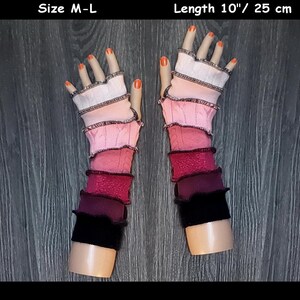 May include: A pair of fingerless gloves with a multi-colored striped design. The gloves are pink, red, and black. The gloves are 10 inches long and are size M-L.