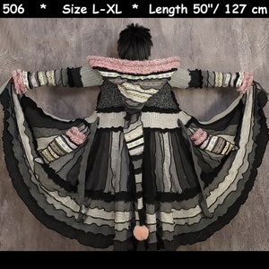 May include: A long, black and grey striped cardigan with a pink hood and ruffled trim. The cardigan is made of a variety of fabrics and textures, and has a unique, layered design. It is 50 inches long and available in sizes L-XL.