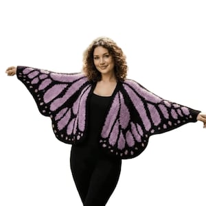 May include: A knitted butterfly wing-shaped cardigan in black and lavender. The open-front sweater features a detailed wing pattern, with a solid black border and lavender interior. The sleeves extend to the elbows, creating a dramatic, whimsical look.