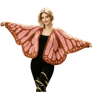May include: A knitted butterfly wing-shaped cardigan in shades of pink and brown. The open-front sweater features a detailed wing pattern, with a brown border and pink interior. The sleeves extend to create the wing shape, perfect for a whimsical look.