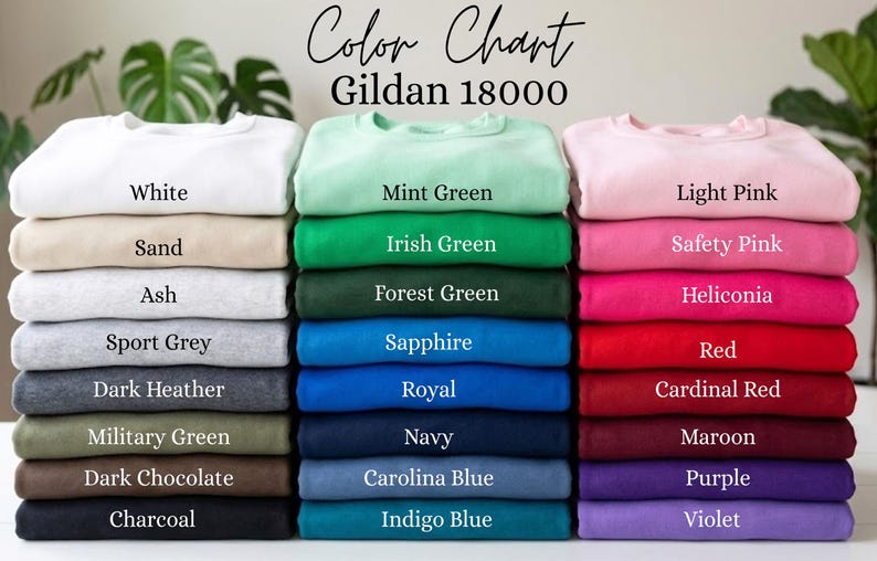 Może przedstawiać: Wzornik kolor&oacute;w bluz Gildan 18000 przedstawiający trzy pionowe stosy złożonej odzieży w r&oacute;żnych kolorach. Tekst brzmi Color Chart Gildan 18000, a po nim następują etykiety dla każdego koloru, w tym biały, piaskowy, popielaty, szary, zielony, niebieski, r&oacute;żowy, czerwony i fioletowy.