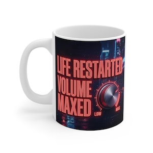 Può includere: Tazza in ceramica bianca con la scritta "LIFE RESTARTED VOLUME MAXED" in lettere rosse al neon. Il design include una manopola del volume e uno sfondo di paesaggio urbano. La tazza ha un manico curvo.