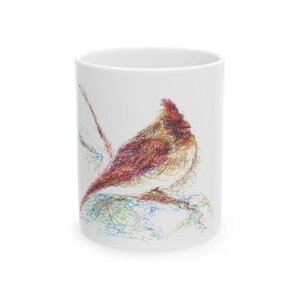 May include: White ceramic mug featuring a colorful, abstract illustration of a cardinal bird. The bird is depicted with intricate lines in shades of red, brown, purple, and blue. The mug is a standard size, perfect for coffee or tea.