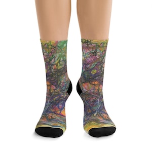 May include: A pair of crew socks with a colorful abstract design. The socks feature a mix of green, purple, orange, and yellow hues with black accents. The toe and heel are black.