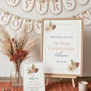 Puede incluir: Un cartel de bienvenida para una primera comunión en un marco de madera clara, una tarjeta de invitación a juego y una pancarta con el texto MY FIRST COMMUNION. El conjunto presenta hierba de la pampa seca, hojas de palma y detalles florales.