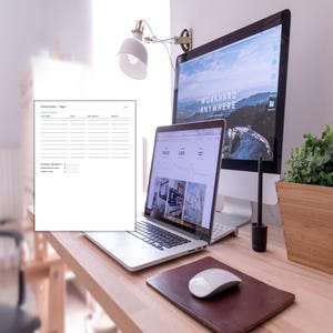 Pode incluir: Uma configuração de escritório moderna com um laptop, um monitor de desktop e um documento impresso. O monitor de desktop exibe o texto "WORKHARD ANYWHERE" em um fundo cênico. Um mouse branco e um mousepad de couro estão na mesa.