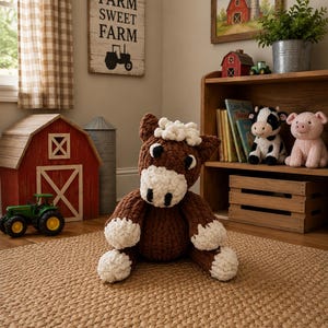 May include: A brown and white crocheted horse plush toy with a textured yarn finish, featuring a white muzzle, white hooves, and a white mane. The stuffed animal is seated in a neutral position, showcasing its soft, chunky yarn construction.