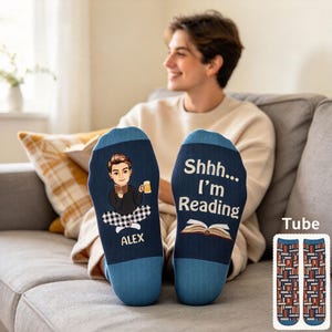 May include: A pair of blue socks featuring a cartoon illustration of a person reading a book while holding a mug, with the name ALEX printed below. The other sock displays the text Shhh... I'm Reading above an open book graphic.