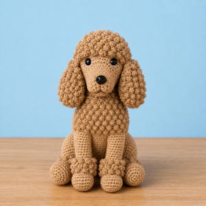 May include: A handmade, tan crochet poodle dog sits on a wooden surface against a light blue background. The poodle has a textured, curly appearance, with round eyes and a black nose. The dog's legs and paws are also crocheted.