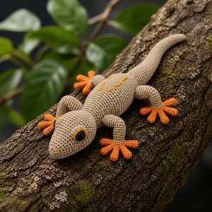May include: A crocheted gecko in tan and orange, resting on a tree branch. The handmade reptile features orange feet, yellow markings, and black eyes. The gecko is a detailed, textured craft item.