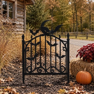 Può includere: Un pannello di recinzione da giardino in metallo nero con una parte superiore ad arco decorativa che presenta una mezzaluna e diverse sagome di pipistrelli. Le barre verticali sono decorate con volute alla base e punte sui due pali.