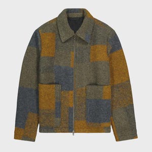May include: A long-sleeve jacket featuring a color-blocked pattern in shades of olive green, mustard yellow, and slate blue. The jacket has a fold-over collar, a full-length metal zipper closure, and two large square patch pockets on the front.